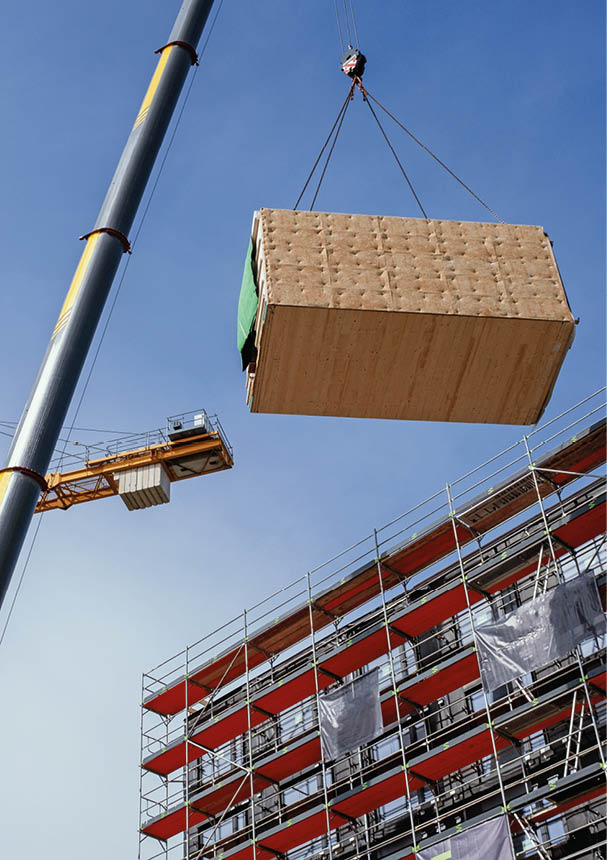 Crane lifting a wooden building module to its position in the structure  Construction site of an office building in Berlin  The new structure will be built in modular timber construction 