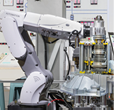 Engineer using laptop computer for maintenance automatic robotic hand machine tool in automotive industry